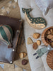 A cozy scene with a vintage suitcase, green whale-shaped night light, Hot Air Balloon - Light Brown / Green decor, wooden blocks, wicker basket, and fabric rabbit doll on a textured rug—perfect for charming children's room decoration.