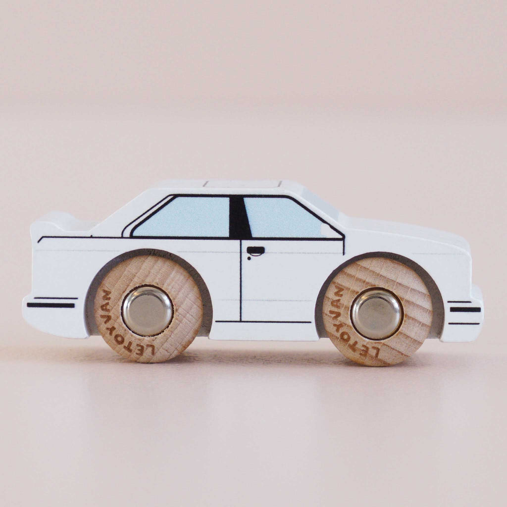 The No. 21 GT120 William, a white wooden racing car with simple black outlines and natural wood wheels, made in England and reminiscent of a retro toy car, is photographed on a light background.