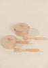 The Wooden Pots and Pans Playset (6 Pcs), featuring two wooden toy pots with lids, a wooden spoon, and a wooden spatula arranged on a light beige surface, makes the perfect addition to any wooden play kitchen or kids cooking set.