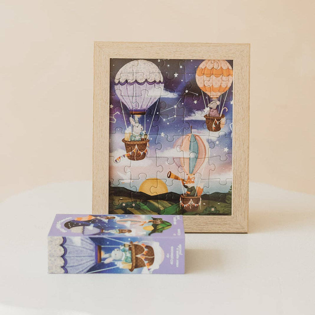 Framed Sky High Friends 40 Piece Mini puzzle featuring whimsical animals in hot air balloons floating at night, with the matching illustrated box displayed in front on a white surface.