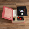 An open Board Game: Scattergories Vintage Bookshelf Edition box on a wooden floor displays the rulebook, answer pads, pencils, timer, die, and category cards neatly inside—echoing the classic 1988 version.