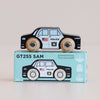 A black wooden police car featuring U.S. flag and badge details rests atop a matching illustrated box labeled “No. 41 GT255 Sam | Made in England.” This classic toy encourages imaginative play and is suitable for ages 2 and up.