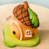 The Bumbu Handmade Wooden Acorn House features a brown textured roof, green leaf detail, round door, and tiny window on a green base—perfect as a Montessori Waldorf toy or whimsical fairy dwelling.