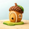 The Bumbu Handmade Wooden Acorn House is a whimsical toy shaped like an acorn, featuring a brown textured cap roof, green leaf detail, arched door, and small window—an enchanting fairy home inspired by Montessori Waldorf design.