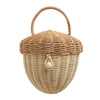 A round, handwoven Olli Ella Rattan Acorn Bag with a lid and a curved handle, featuring a decorative seashell attached to the front.