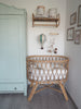 A cozy nursery corner with a rattan crib, wooden shelf, and mint green wardrobe; by the crib hangs the Hot Air Balloon – Mint Green and Grey, its handmade wooden basket adding playful charm to the soft-colored space.