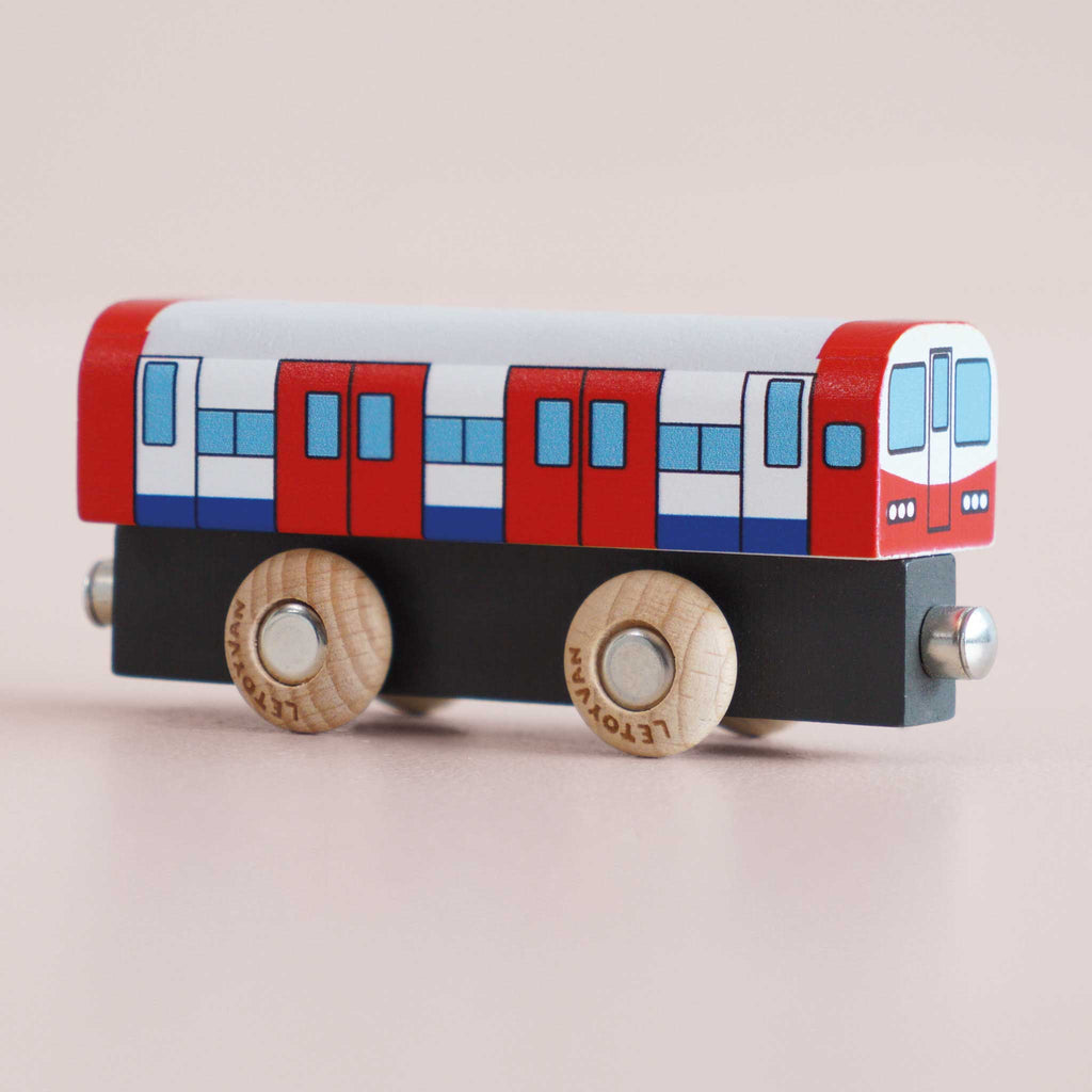 The No. 48 GT290 Tim, made in England, is a wooden toy train car adorned with red, white, and blue painted details. Featuring four wooden wheels and metallic connectors on both ends, it invites imaginative play as children explore the world of metro transport on a light surface.