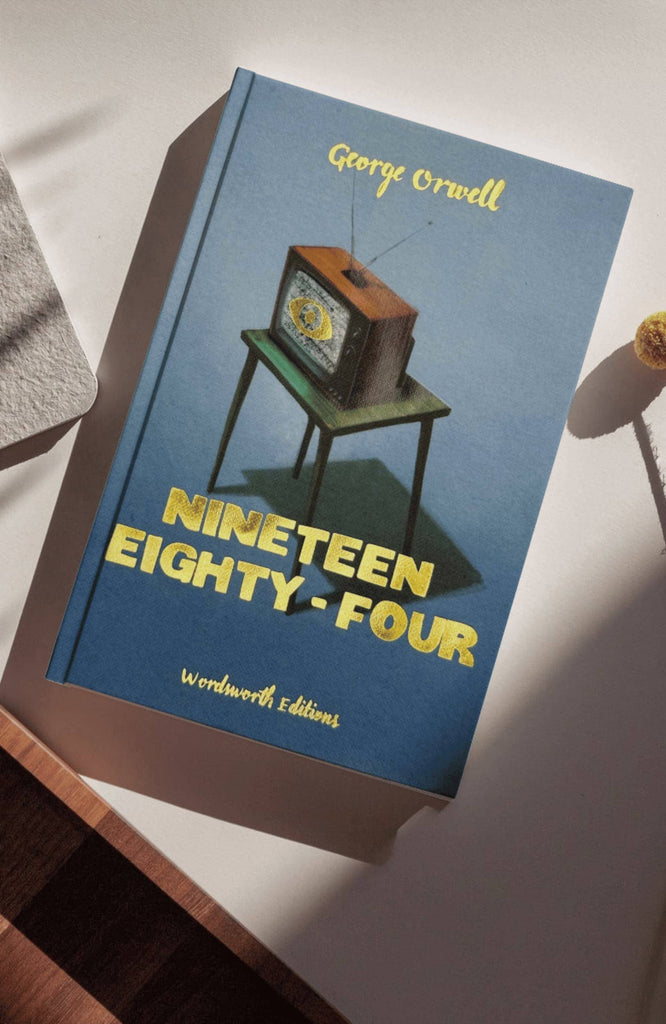 A hardcover collector’s edition of "1984 George Orwell" rests on a white surface. The cover shows a vintage TV casting a shadow, alluding to the novel’s dystopian themes, with "Wordsworth Editions" printed below.