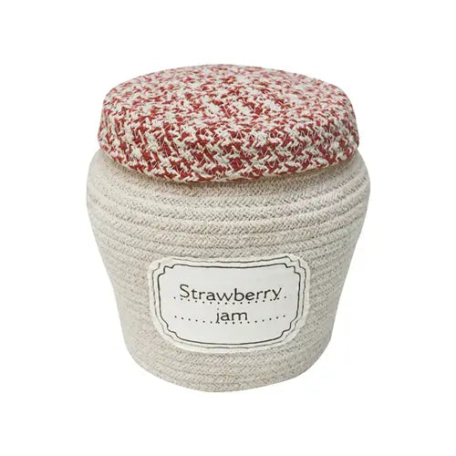 A jar of Strawberry Jam Jar Basket covered with a cozy, knit fabric cap in red and white, wrapped by a beige rope.
