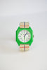 A Mini Kyomo Watch x Taxi Brousse - Color Notebook with a green square case, white dial, black/green numbers, and a beige strap with blue and red stripes is shown against a white background.