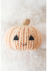 The Cuddle + Kind Baby Ghost with Pumpkin, made from soft Peruvian cotton yarn, features a smiling face and sits on a plush white surface.