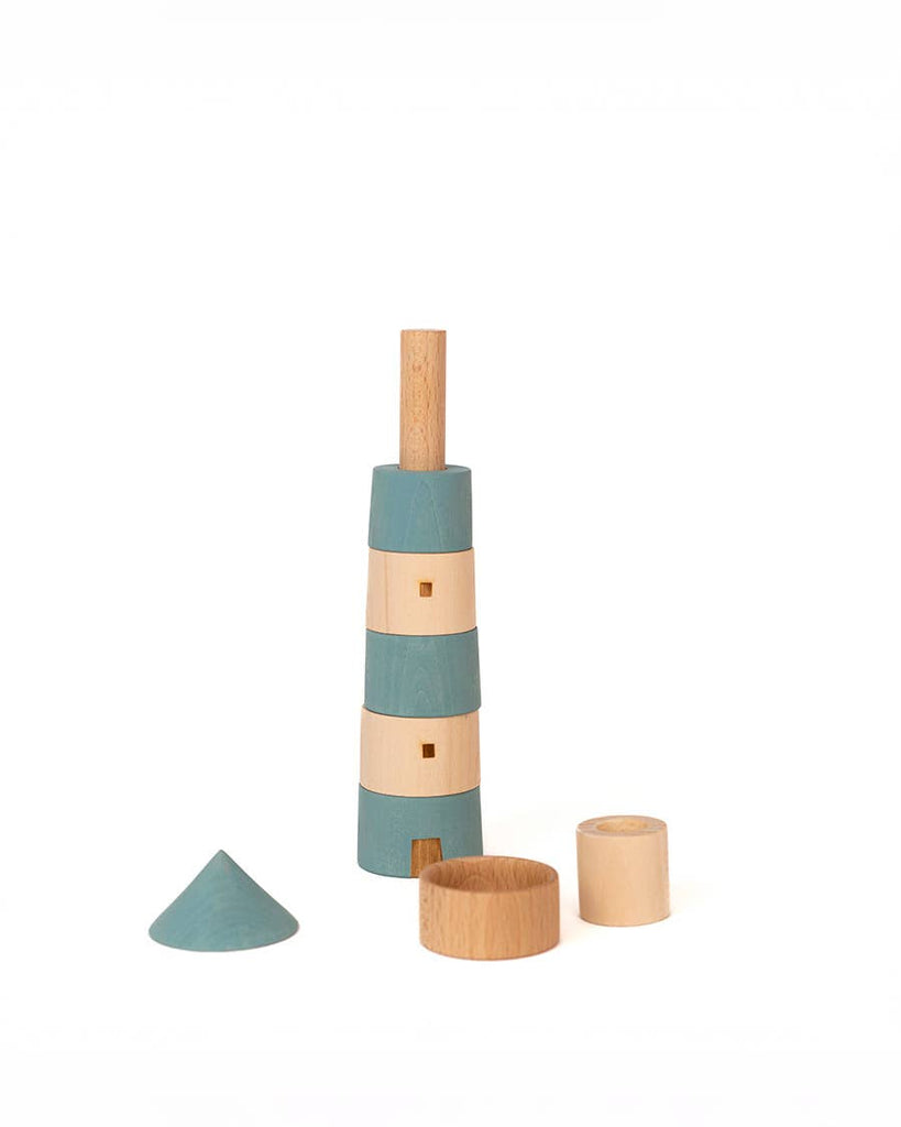 A Sabo Concept Lighthouse wooden toy with alternating blue and natural wood rings, shown stacked with extra loose pieces placed in front.