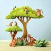 A playful scene featuring Montessori educational toys: two Bumbu Wooden Amazonian Parrots perched on a tall tree, a monkey sitting on a branch, two mice on a smaller tree, and a tiger with its cub resting by bushes. The bright green foliage enhances this whimsical setting created from eco-friendly materials.