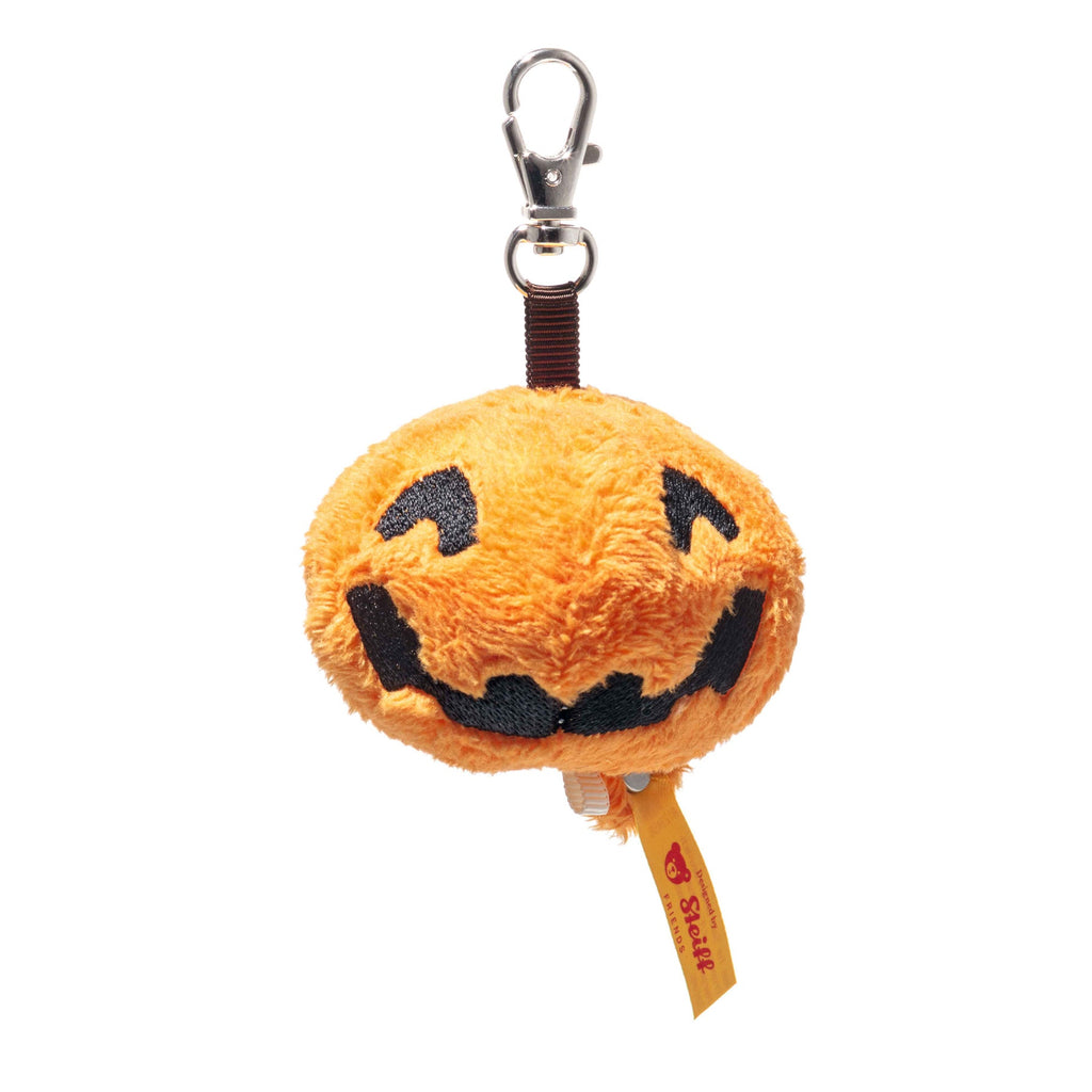 The Steiff Little Pumpkin Keychain features a plush orange pumpkin with a jack-o’-lantern face, black details, silver clasp, yellow Steiff tag, and the iconic Button in Ear—perfect as a festive Halloween keyring.