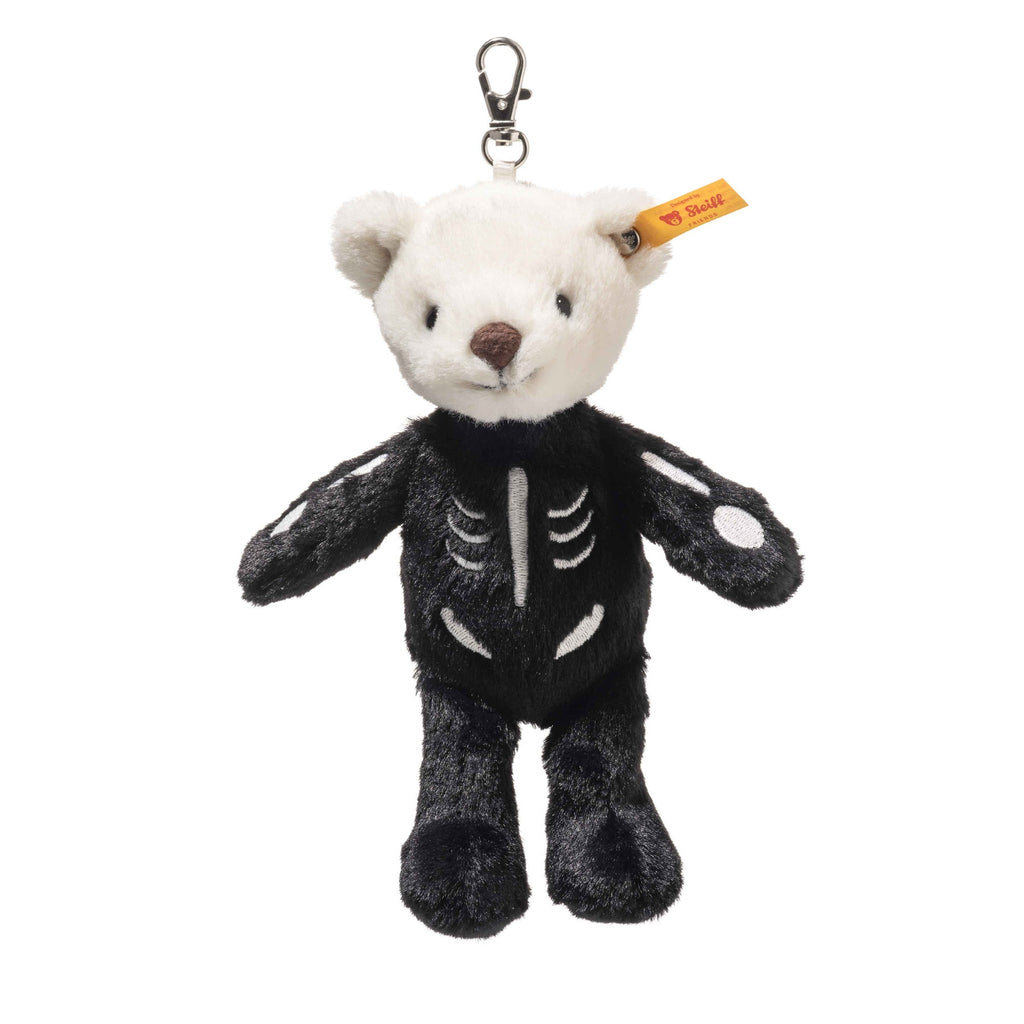 The Steiff Mr. Bones Teddy Bear Keychain features a white head, black body with skeleton design, yellow ear tag, and a metal clasp for easy hanging—perfect as a Halloween-themed accessory.