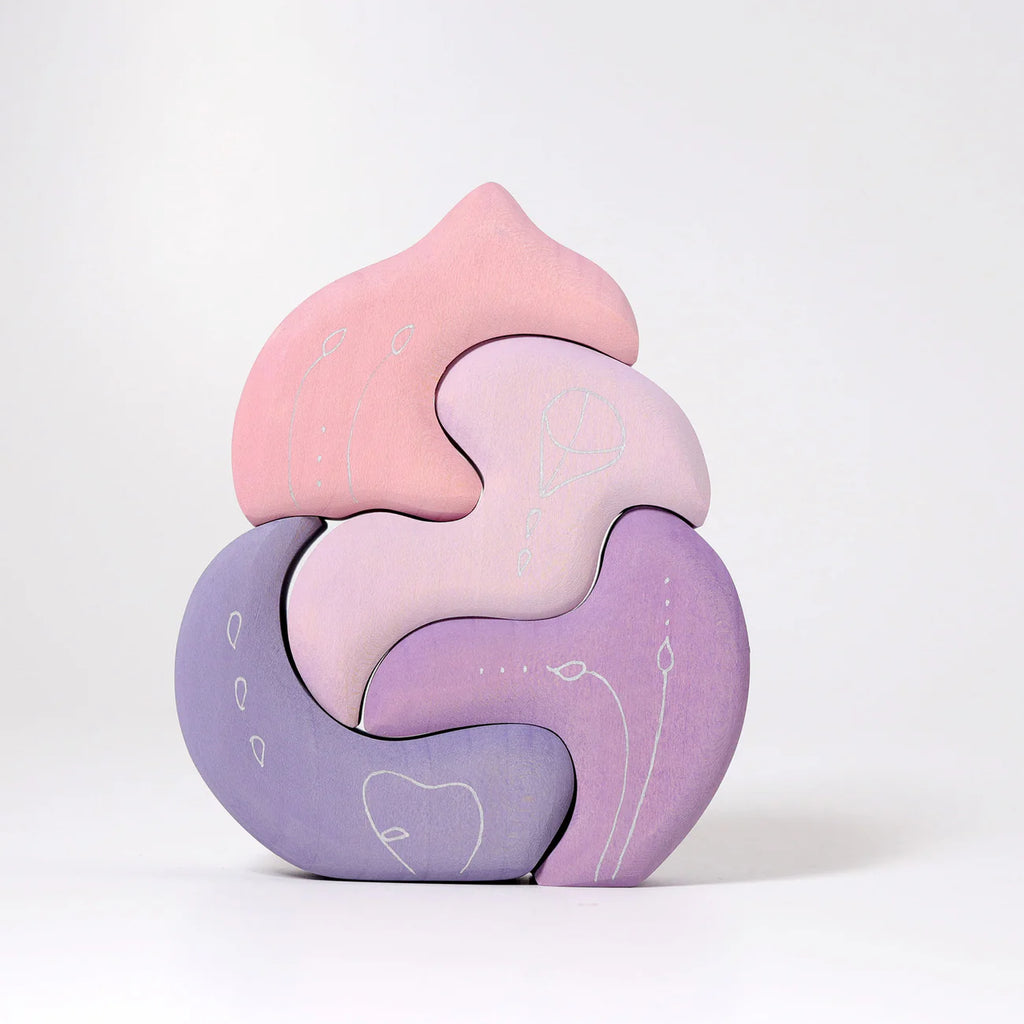 Grimm’s Casa Coral Building Blocks is a pastel-colored wooden puzzle, handpainted in pink and purple tones. With five interlocking pieces and delicate white floral line art, it’s a charming toddler toy shown upright against a white background.