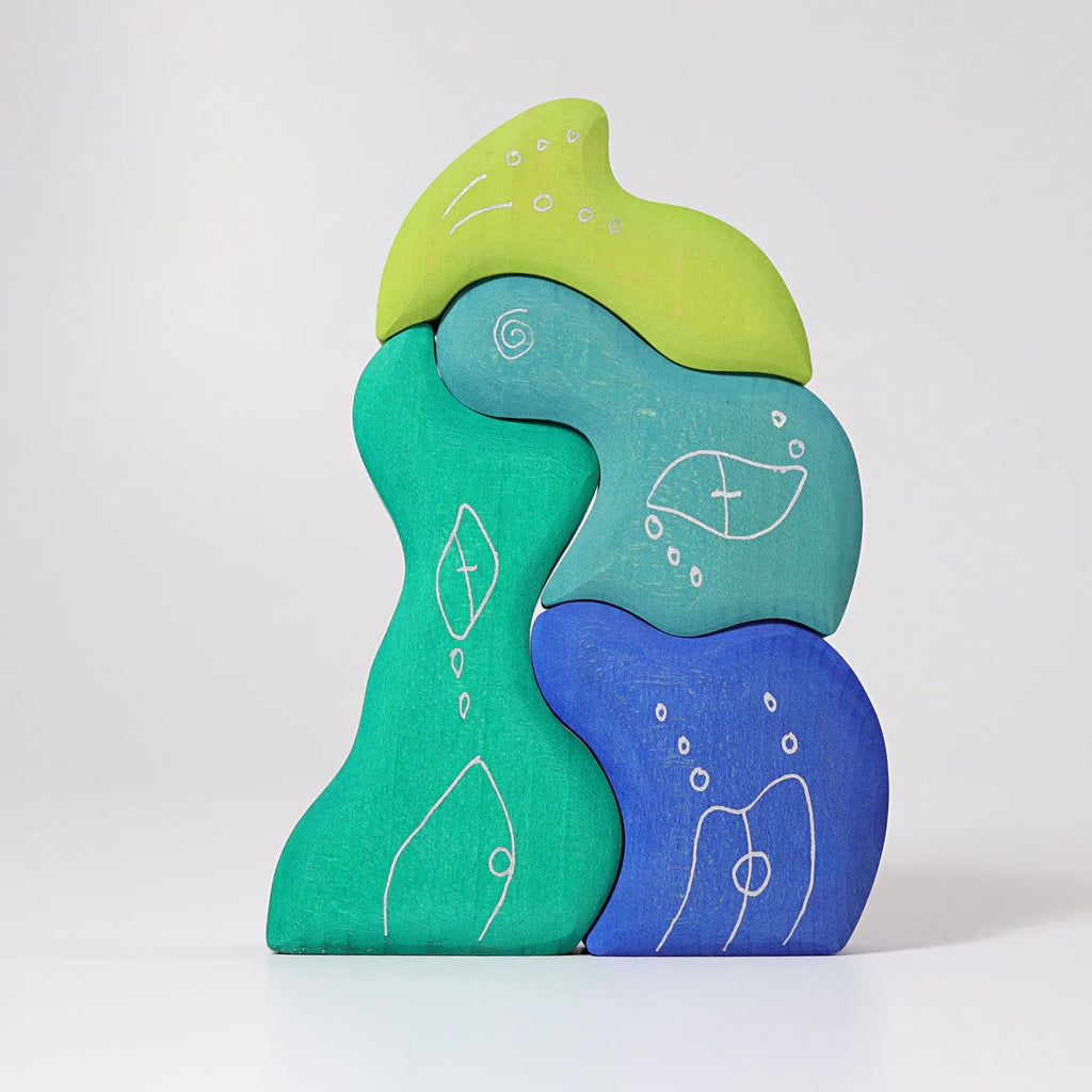 Grimm's Casa Aqua Building Blocks features five abstract, wavy pieces in green, blue, and yellow with white fish and bubble designs, inspiring imaginative play against a plain white background.