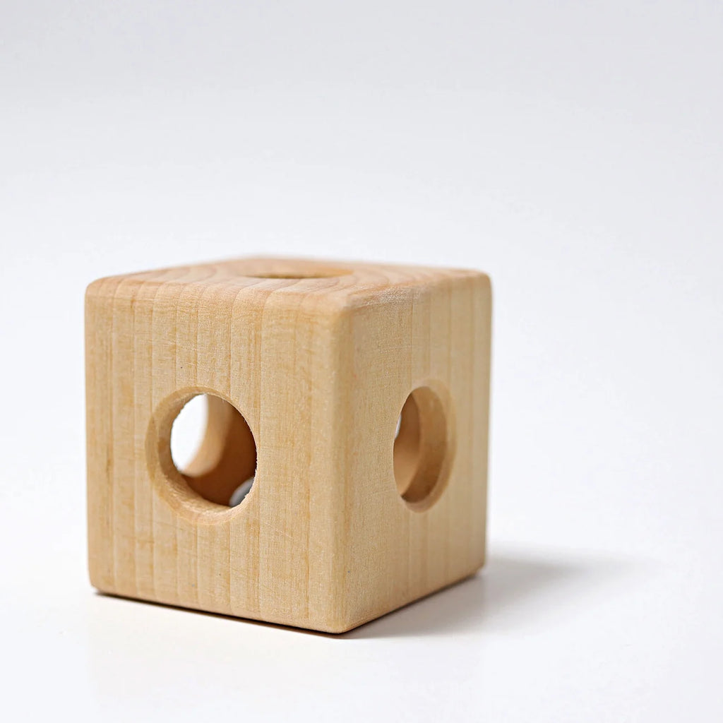 Grimm’s Cube with Bell—featured here on a white surface against a plain white background—is a light, handcrafted wooden toy cube with smooth edges and circular holes on each visible side. Non-toxic and thoughtfully designed for safe play, this baby toy encourages gentle exploration.