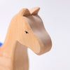 Close-up of Grimm's Horse Holly, a pull-along toy crafted from smooth, light-colored wood with minimal features, including a simple painted eye. The charming wooden horse is set against a plain white background.
