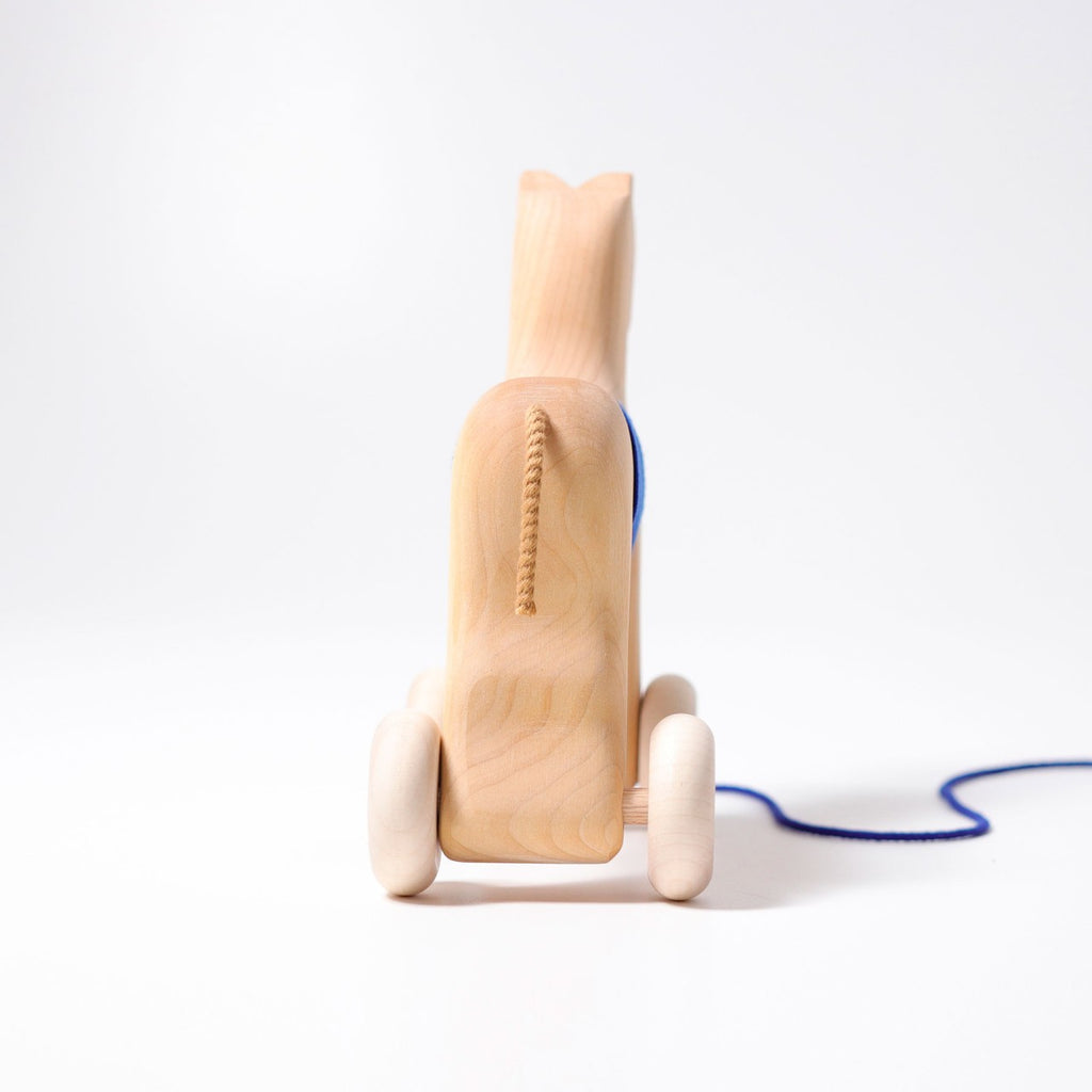 Grimm's Horse Holly is a charming wooden pull-along horse toy with white wheels and a blue string, shown against a plain white background—a timeless classic for toddlers.