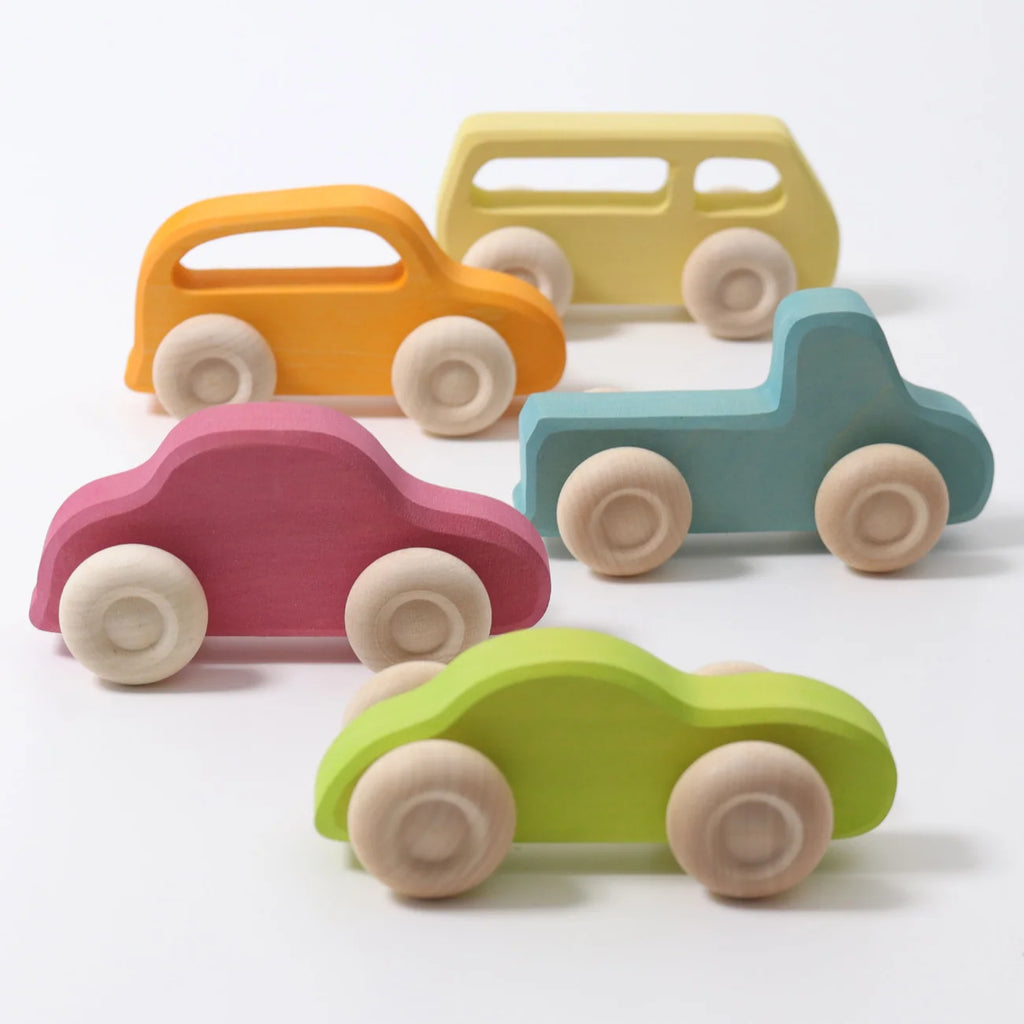 Grimm’s Wooden Cars Slimline, available in orange, yellow, pink, blue, and green, are arranged on a white surface. Each car features simple shapes, smooth natural wood wheels, and a safe finish with natural oils—perfect toddler toys for creative play (ships in 2-3 weeks).