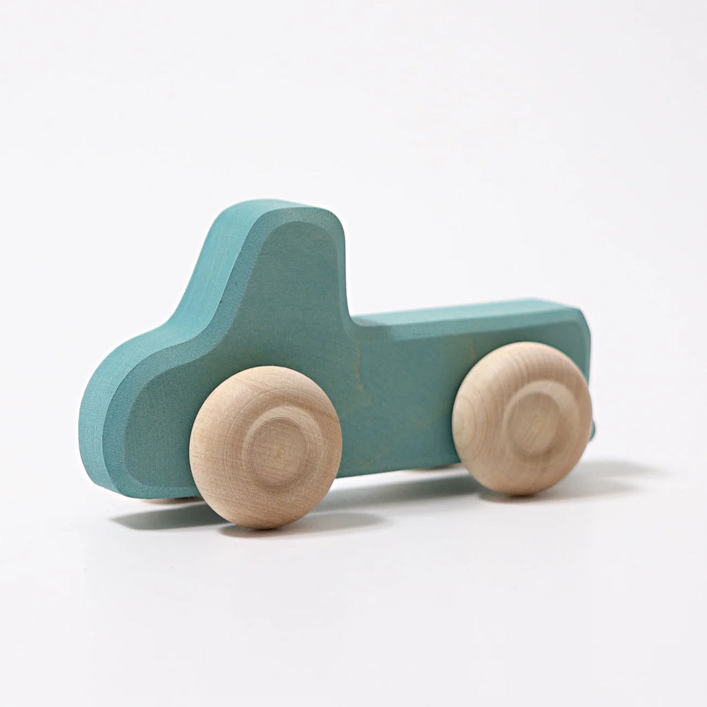 Grimm’s Wooden Cars Slimline—a simple wooden toy truck painted blue with natural, unpainted wooden wheels and a smooth natural oils finish—photographed on a white background, makes an ideal addition to any collection of classic wooden toy cars or toddler toys.