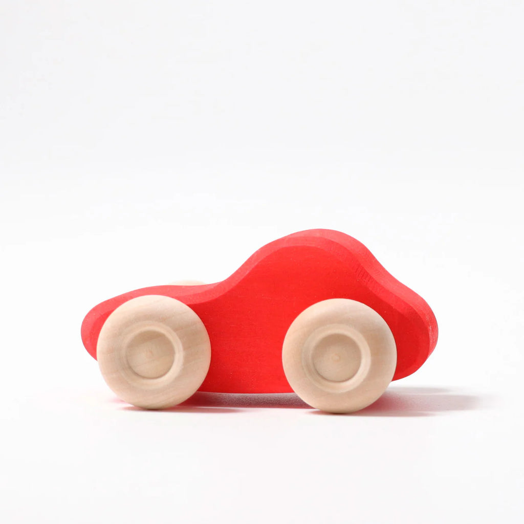A classic non-toxic toy, Grimm's Colored Wooden Cars features a simple wooden design with a bright red body and four natural wood wheels, shown on a plain white background.