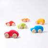 Six Grimm's Colored Wooden Cars in red, blue, green, yellow, and orange sit on a white surface. These non-toxic wooden toys feature simple designs and natural wooden wheels for safe play.