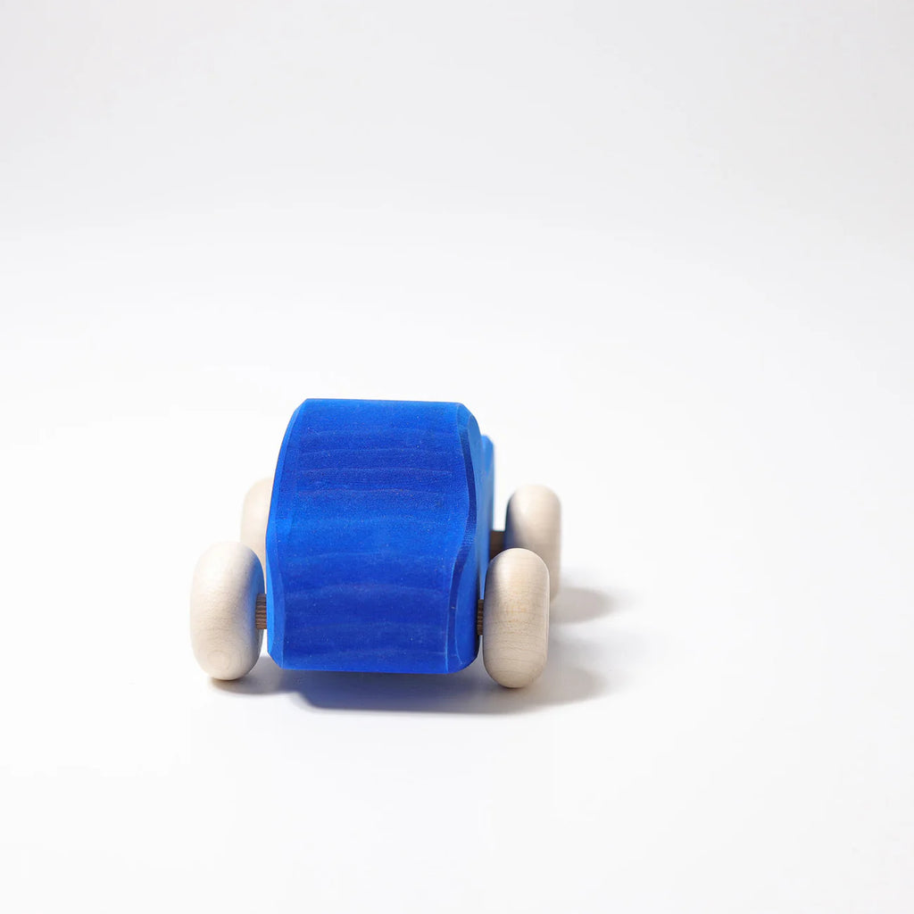 Grimm's Small Blue Truck—a small, non-toxic wood toy with natural wooden wheels—is displayed on a plain white background.