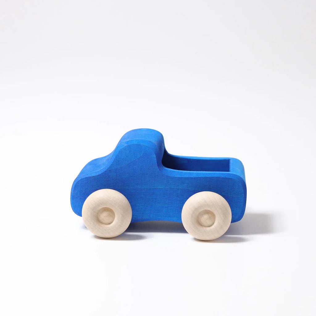 Grimm's Small Blue Truck, crafted from non-toxic wood with natural wooden wheels, is displayed on a plain white background.