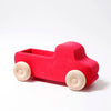 Grimm's Large Red Truck is a simple, non-toxic wooden toy painted red with natural wood-colored wheels, shown against a plain white background.