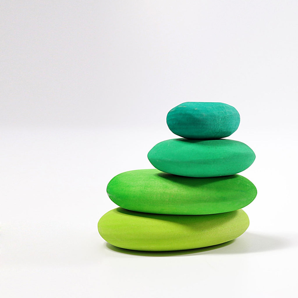 A minimalist stack of four smooth, oval-shaped stones painted in gradient green shades, from light green at the bottom to teal at the top, set against a plain white background. These organic stone shapes evoke a sense of tranquility and balance. The Moss Pebbles Stacker is perfect for fostering a calming and harmonious environment.