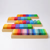 The Grimm's Shapes and Colors Set features four wooden trays with colorful geometric blocks arranged in rainbow gradients, perfect for developing fine motor skills.