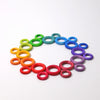 Grimm's Building Rings - Rainbow features colorful wooden rings in various sizes, arranged in a circular gradient to create a vibrant stacking toy that supports fine motor skill development.