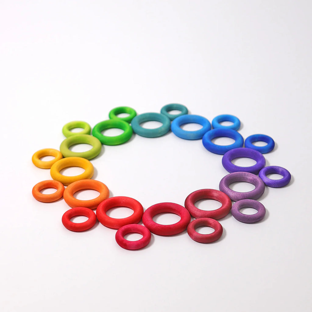 Grimm's Building Rings - Rainbow features colorful wooden rings in various sizes, arranged in a circular gradient to create a vibrant stacking toy that supports fine motor skill development.