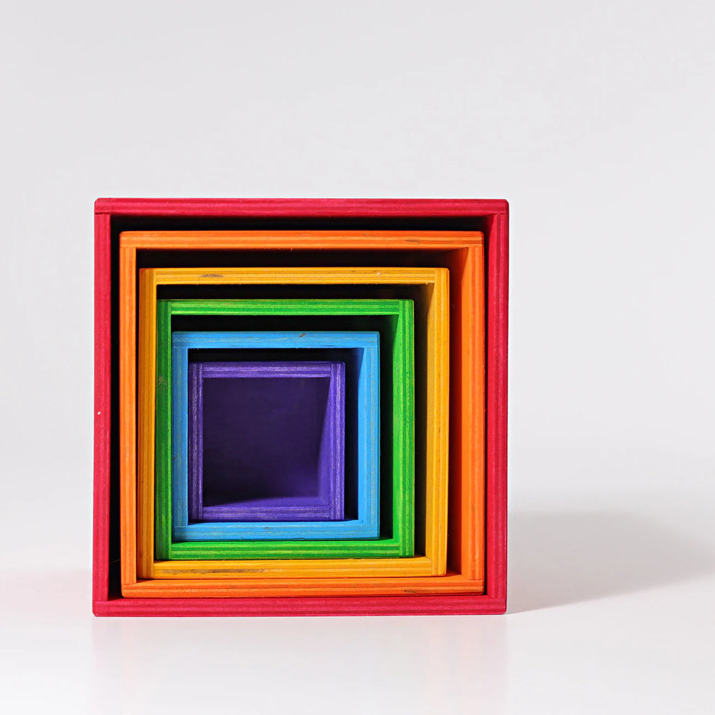 Grimm's Large Set of Boxes - Rainbow features colorful, non-toxic wooden stacking boxes in various sizes and rainbow hues, neatly nested together and shown from the front on a plain white background.