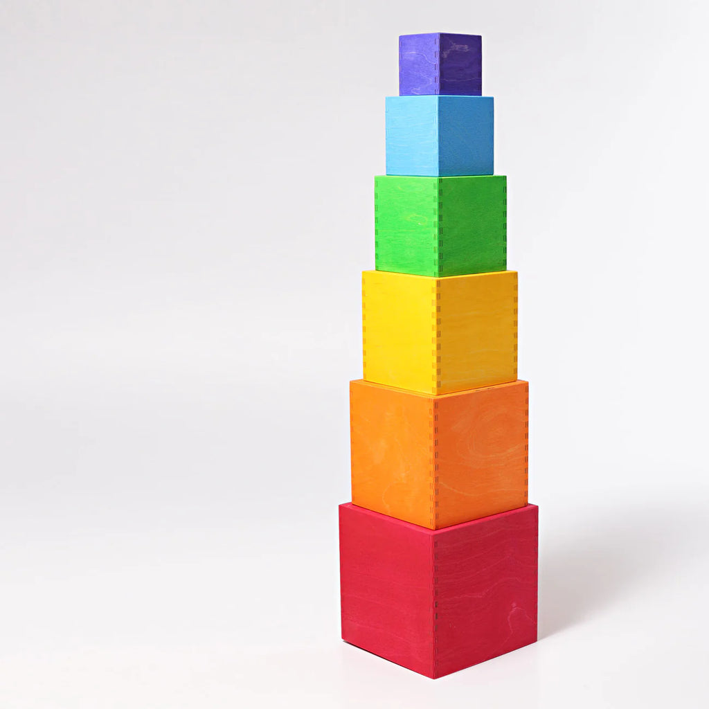Grimm's Large Set of Boxes - Rainbow features six non-toxic wooden boxes in descending sizes, colored red, orange, yellow, green, blue, and purple, stacked vertically like rainbow toys against a white background.
