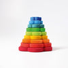 Introducing Grimm's Flower Stacking Tower: a vibrant children's stacking toy featuring a blue central peg. The non-toxic pieces come in various colors and sizes, from small blue and green flowers to larger red, orange, and yellow blooms. Each flower boasts multiple holes that encourage the development of fine motor skills as they are arranged around the peg.