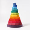 A Grimm's Giant Geometrical Stacking Tower with sixteen pieces, each progressively smaller in size from bottom to top. Made of non-toxic wood, it ranges in color from dark purple at the base to bright blue at the top, creating a gradient rainbow effect. Ideal for developing fine motor skills, it sits against a plain white background.