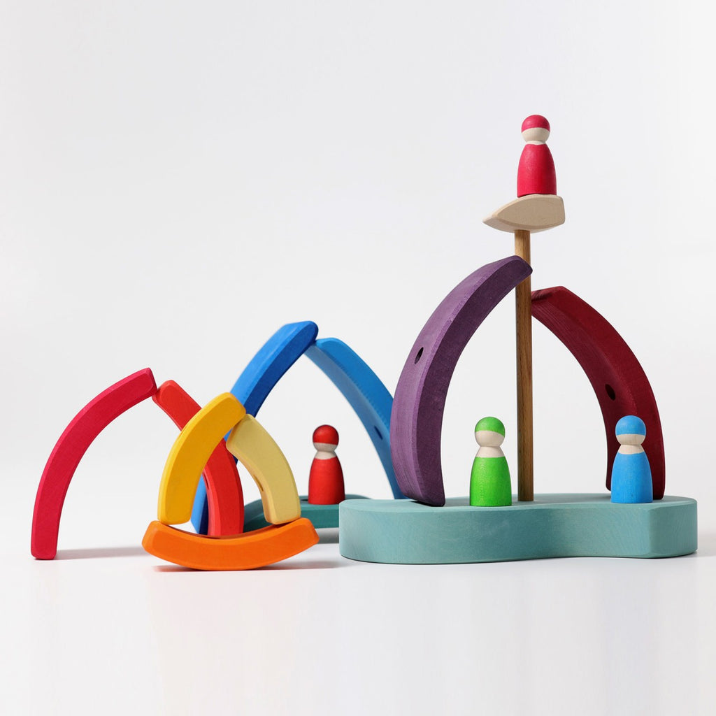 Grimm's Stacking Tower Sailboat is a colorful wooden stacking puzzle with sailboat-shaped pieces and pegs, inspiring creativity and developing fine motor skills through playful, abstract arrangements on a white background.