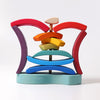 The Grimm's Stacking Tower Sailboat is a colorful wooden puzzle with curved pieces in red, purple, yellow, green, and blue on a central pole and base to enhance fine motor skills.