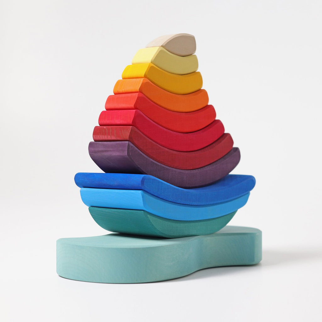 The Grimm's Stacking Tower Sailboat is a colorful stacking puzzle with gradient pieces from blue to cream, designed to develop fine motor skills. Shaped like a sailboat, it stands out beautifully against a plain white background.