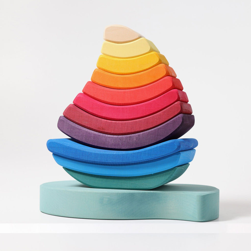 The Grimm's Stacking Tower Sailboat is a colorful wooden puzzle with curved pieces in blue, purple, red, orange, yellow, and cream—ideal for building fine motor skills as kids stack them from largest to smallest.