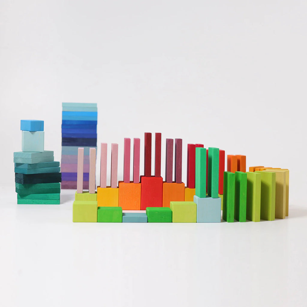 Grimm's Color Charts-Rally features vibrant wooden blocks of different heights and shapes, arranged in gradient rows from blues and greens to reds, oranges, and yellows—ideal for building fine motor skills.