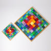 Two square wooden boards featuring colorful, raised square tiles in a symmetrical gradient from yellow and red at the center to greens and blues at the edges, inspired by Grimm's Stepped Pyramid Block Set - Small, handcrafted in Germany.