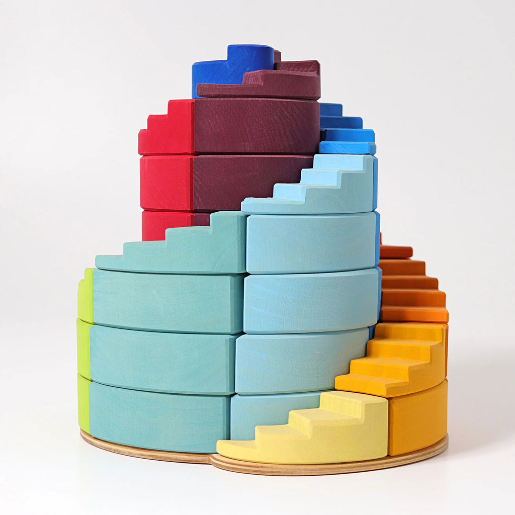 Grimm's Counterrotating Stepped Spiral features colorful wooden blocks in yellow, blue, and red on round bases. The interlocking pieces help children develop fine motor skills as they build spiral staircases and tower structures.