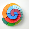 Grimm's Counterrotating Stepped Spiral is a vibrant wooden puzzle with red, green, blue, yellow, and orange pieces arranged in a spiral—ideal for building fine motor skills.