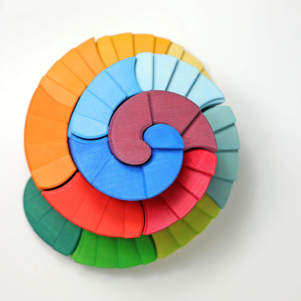 Grimm's Counterrotating Stepped Spiral is a vibrant wooden puzzle with red, green, blue, yellow, and orange pieces arranged in a spiral—ideal for building fine motor skills.