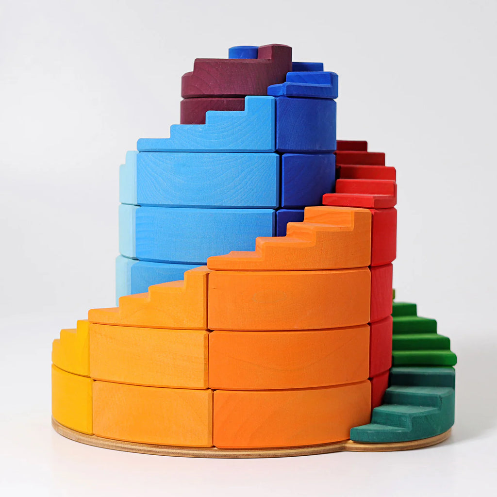 Grimm's Counterrotating Stepped Spiral is a colorful wooden stacking toy with curved, spiral pieces in yellow, orange, red, blue, green, and purple on a round base.