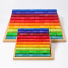 Two wooden trays, each filled with Grimm's Stepped Counting Blocks - Small (coming soon), display non-toxic rainbow blocks arranged in vibrant order from red to blue, with one tray slightly in front of the other on a white surface.